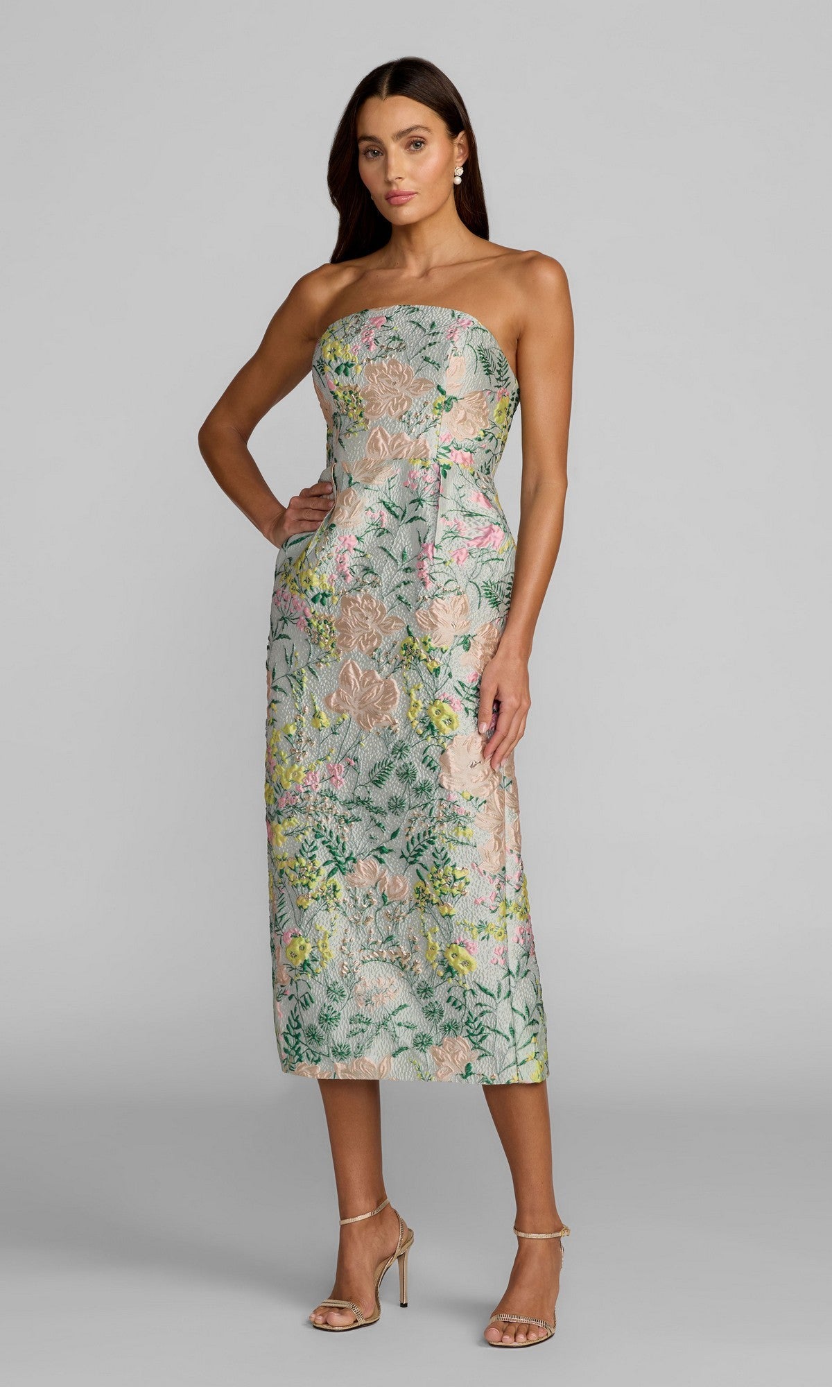 A woman wearing the Mac Duggal 13223 Tea-Length Party Dress in Pastel Multi stands in heels against a plain gray background.